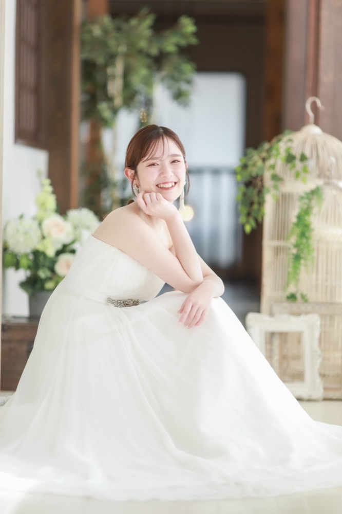 アンティーク調のスタジオで頬杖をついて微笑む花嫁