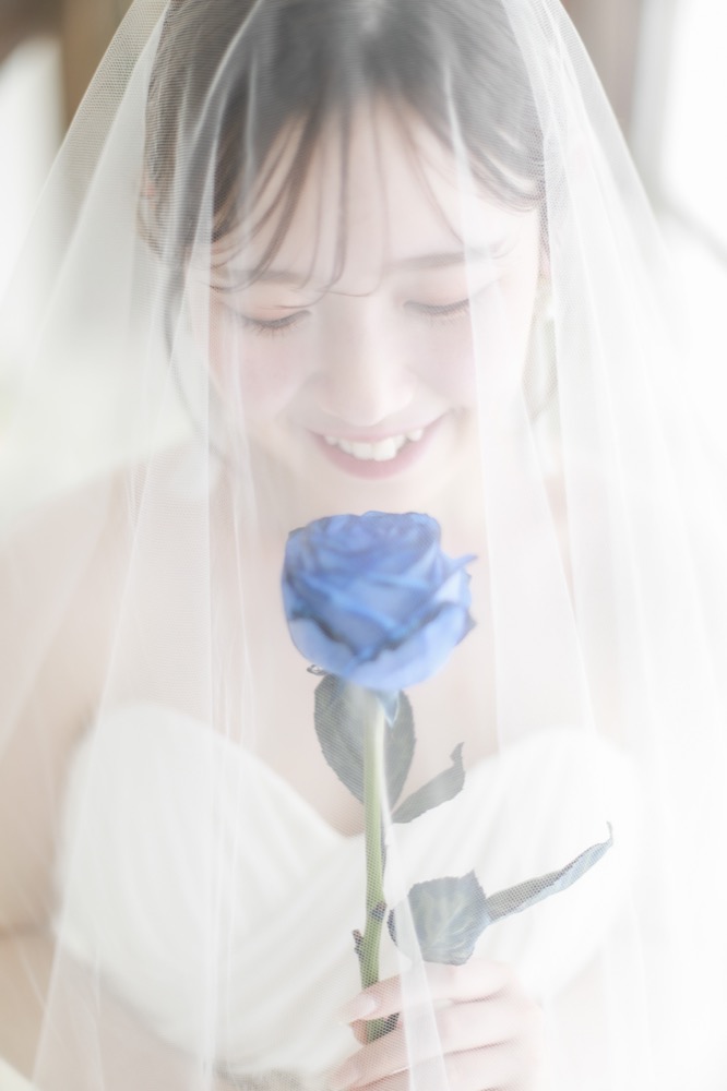 ベール越しにブルーローズを見つめる花嫁のクローズアップ